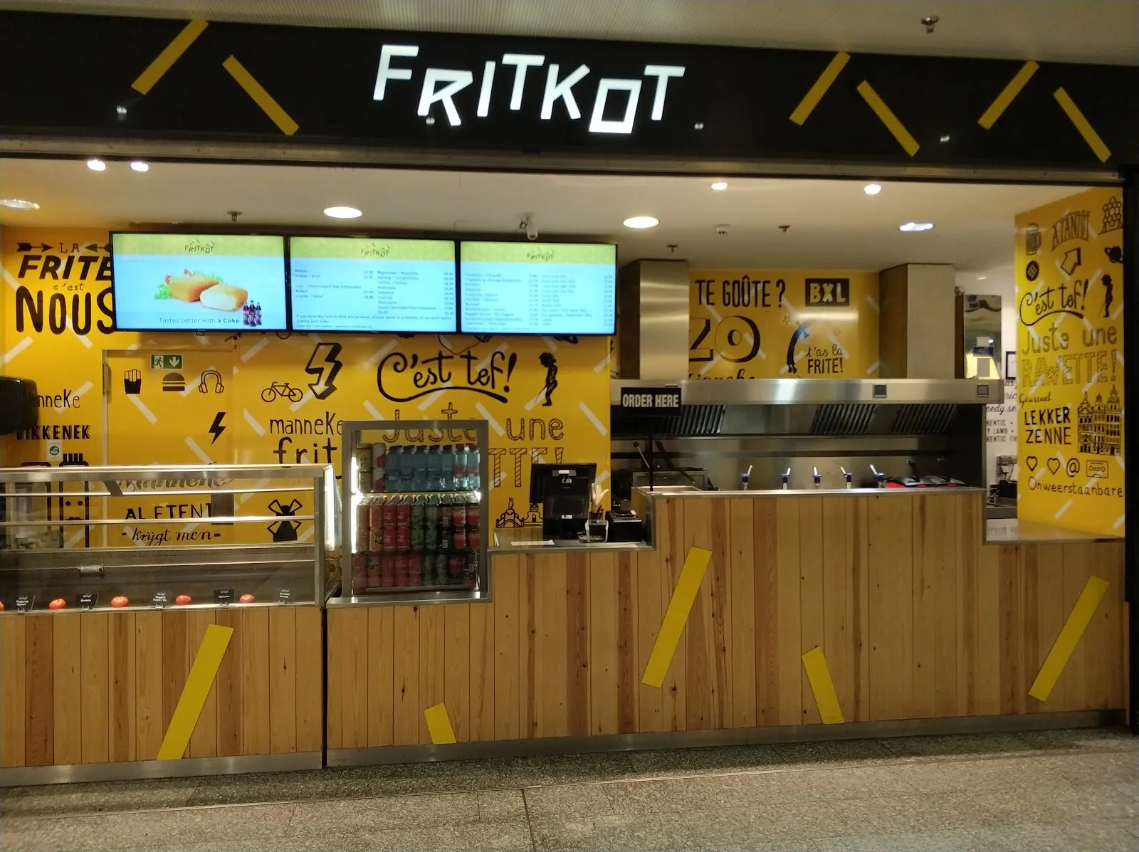 Un cornet de frites mayonnaise et une fricadelle devant une friterie